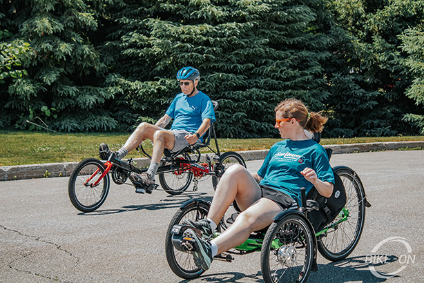 Two cyclists riding recumbent cycles down an open road