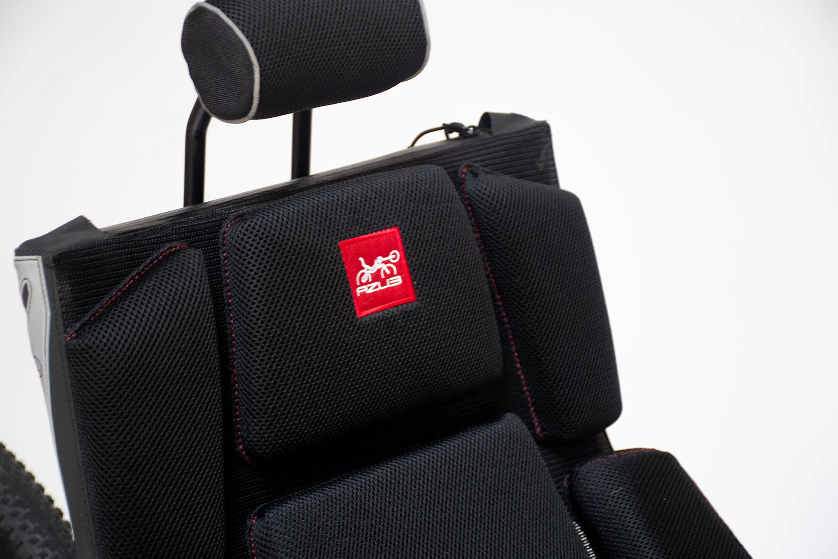 Azub Ti-FLY X black seat with red logo tag positioned below the headrest that reads "AZUB" in white threading