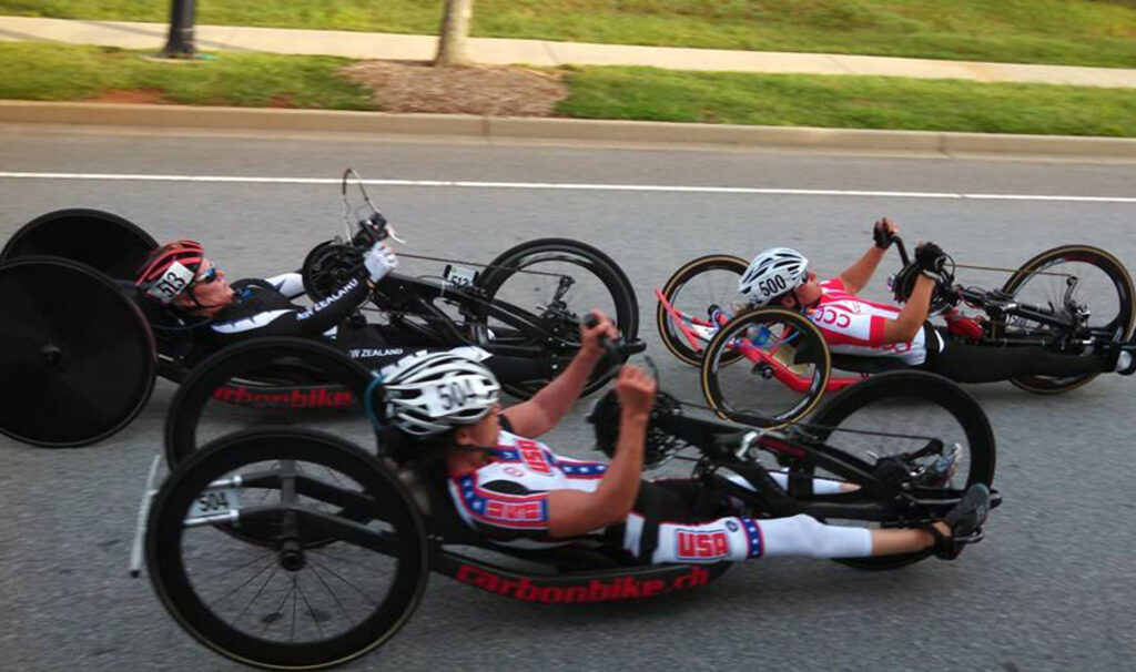 3 handcyclists racing on a paved road